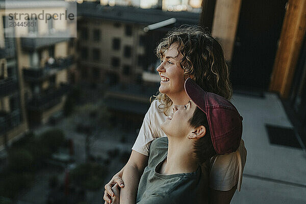 High angle view of happy lesbian woman leaning on girlfriend at balcony