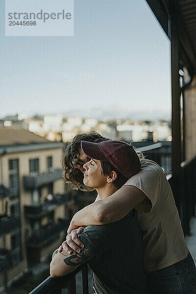 Lesbian woman kissing girlfriend while standing in balcony