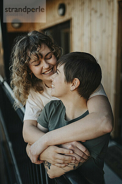 Happy lesbian couple embracing while standing in balcony