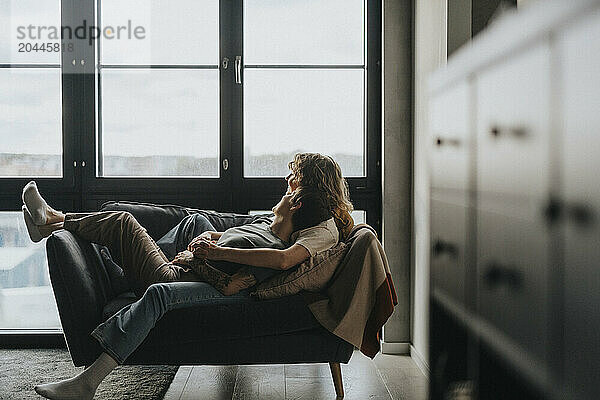 Happy lesbian couple lying on sofa at home