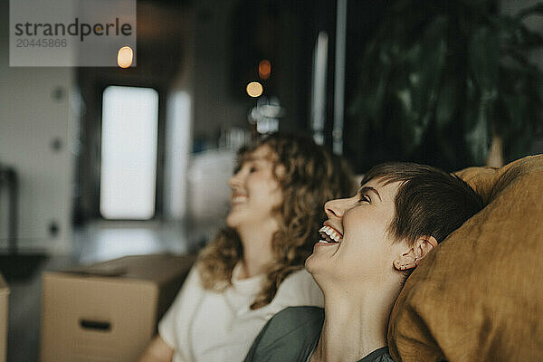 Cheerful lesbian couple laughing during relocation at home