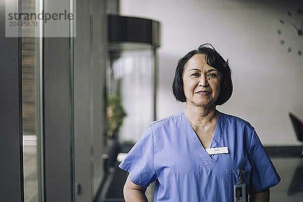 Portrait of confident female senior healthcare worker in medical scrubs at hospital