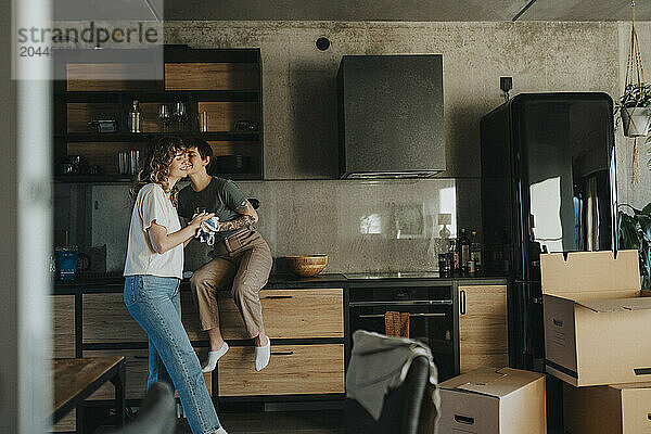 Romantic lesbian couple doing housework in kitchen during relocation