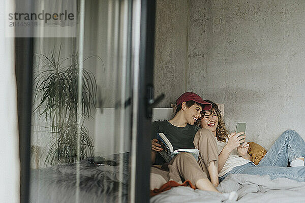 Happy lesbian couple spending leisure time while lying on bed at home