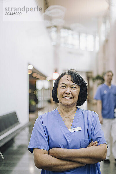 Portrait of smiling female doctor with arms crossed in hospital lobby