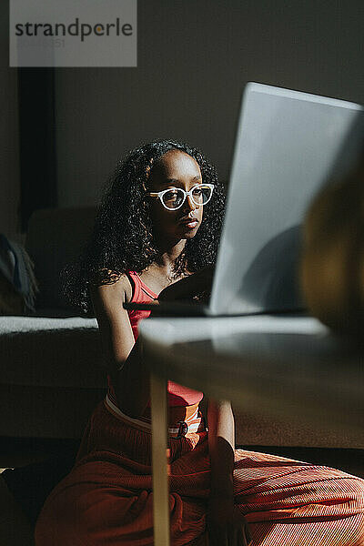 Girl wearing eyeglasses studying on laptop at home