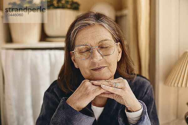 Smiling senior woman with eyes closed at home