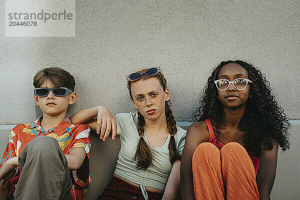 Friends sitting on ground against wall