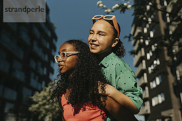 Teenage girl piggybacking female friend at street