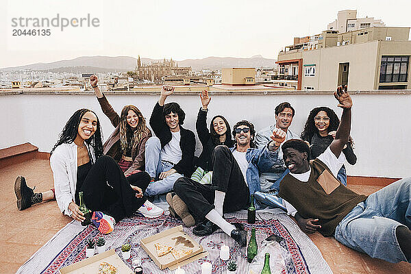 Group of cheerful male and female friends celebrating party with each other on rooftop