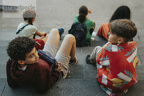 High angle view of male and female friends sitting on staircase