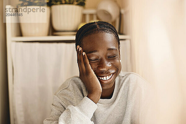 Happy teenage boy with eyes closed at home