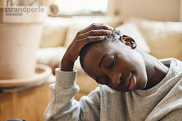 Teenage boy stretching head at home