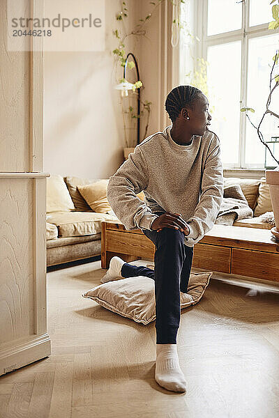 Teenage boy stretching in living room at home