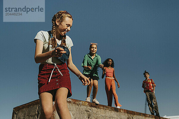 Low angle view of smiling girl having fun with friends against blue sky