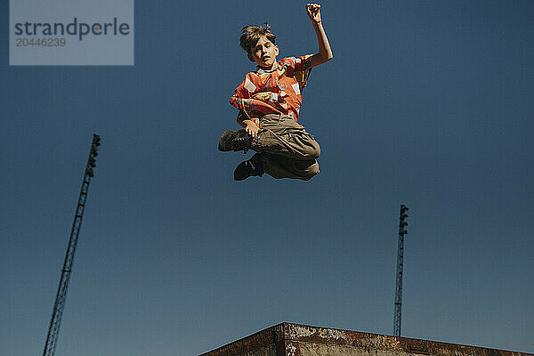 Boy jumping in mid-air against blue sky