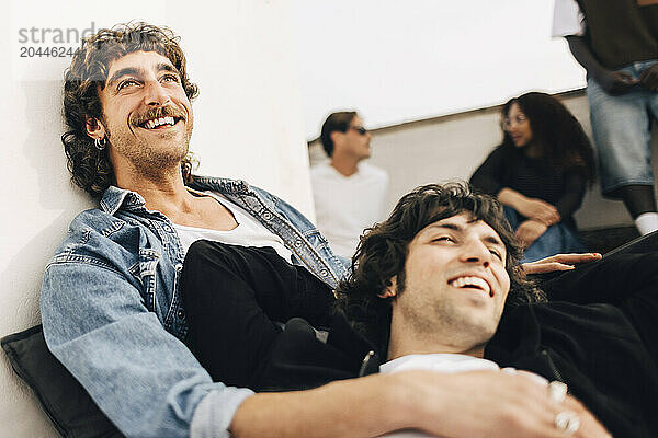 Happy gay couple spending leisure time with each other on building rooftop