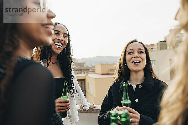 Carefree women having beer and enjoying with each other at rooftop party