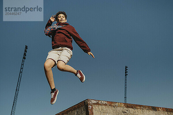 Carefree boy jumping in mid-air against blue sky