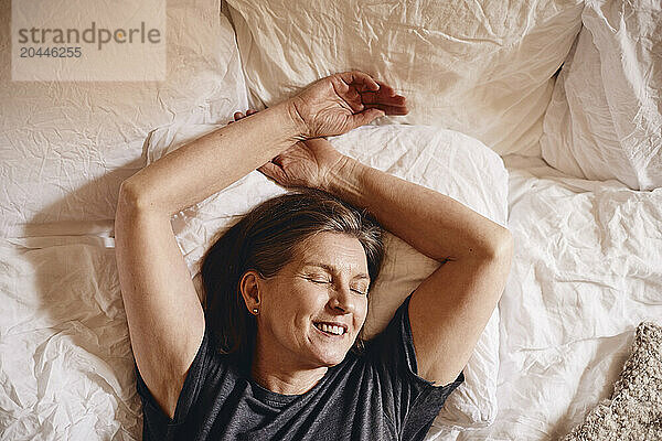 Directly above view of smiling senior woman sleeping on bed at home