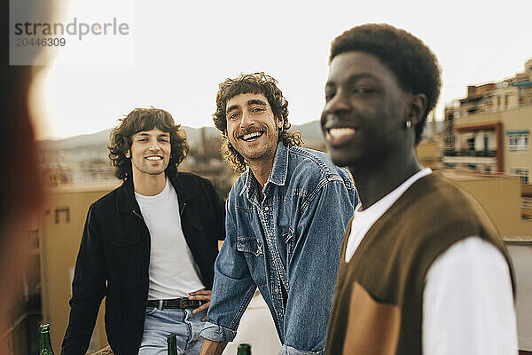 Portrait of smiling man with male friends in party on rooftop