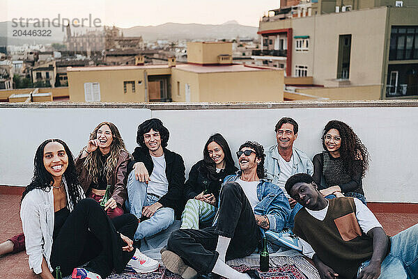 Cheerful group of multiracial male and female friends having fun at rooftop party