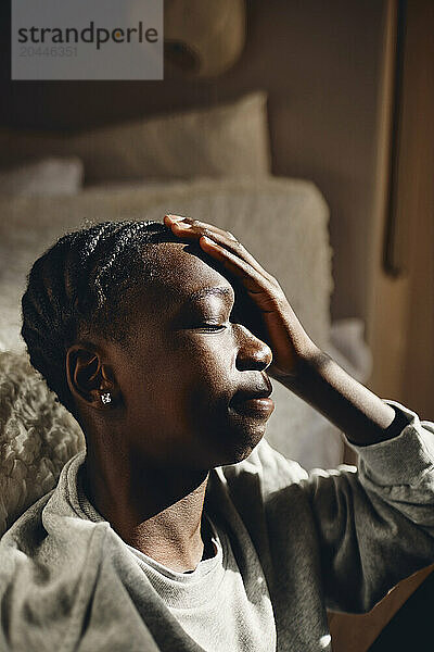 Depressed teenage boy sitting in bedroom at home