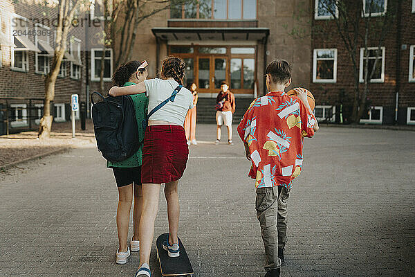 Rear view of boy and girls walking together at school campus