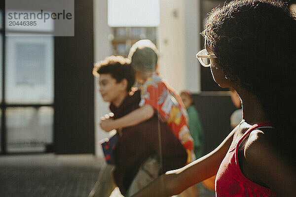 Girl walking with boy piggybacking friend at street