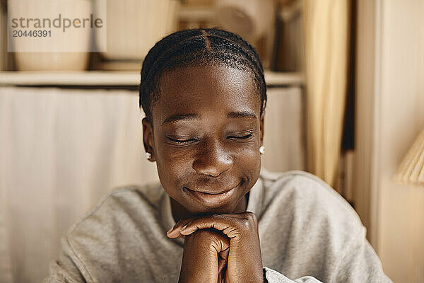 Smiling teenage boy wishing with eyes closed at home