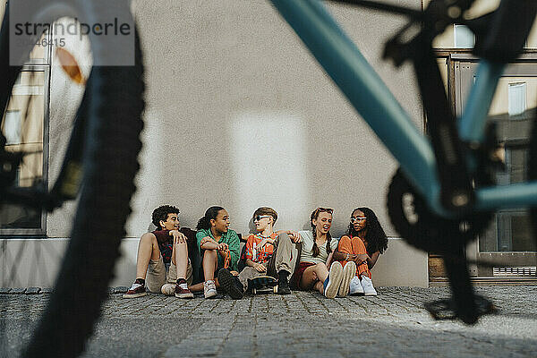 Group of friends sitting on ground against wall