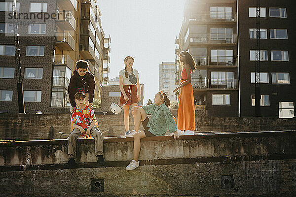 Group of friends sitting on wall against residential buildings