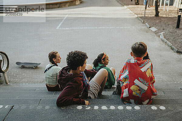 Rear view of group of friends sitting on staircase