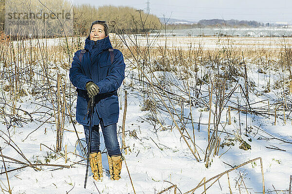 Woman Standing on Snow covered Field Holding Hiking pole