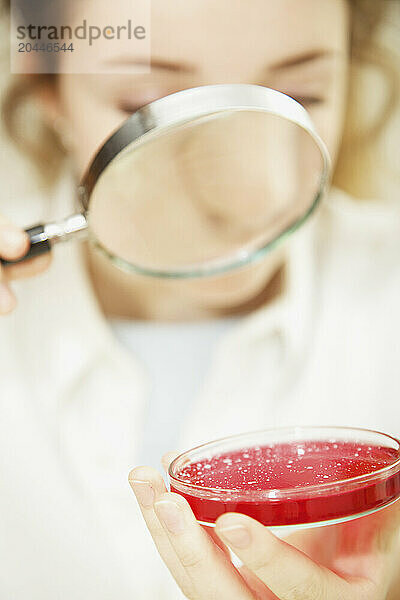 Schoolgirl Examining Cell Culture in Petri Dish with Magnifying Glass