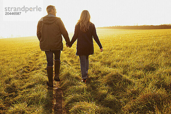 Couple Walking in a Field Holding Hands