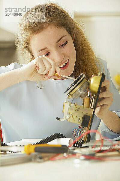 Teenage Girl Building a Telephone for Engineering School Project