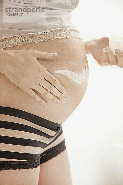 Pregnant Woman Applying Beauty Cream on her Stomach