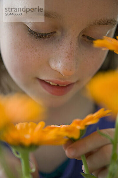 Young Girl Inspecting Orange Flower