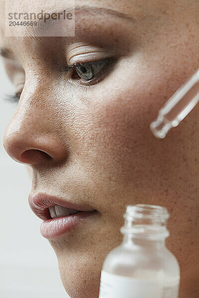 Beauty Portrait of Woman Applying Serum  Close-up view