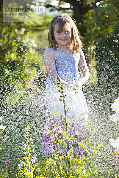 Young Girl Watering Flowers with Garden Hose