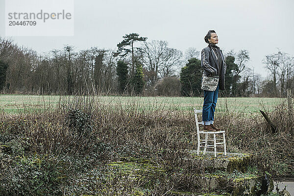 Woman Standing on Chair in a Field