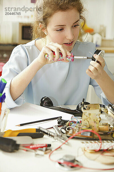 Teenage Girl Building a Telephone for Engineering School Project