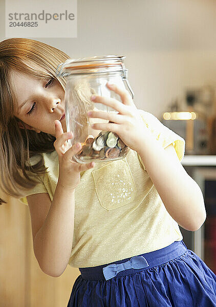 Young Girl Inspecting Jar of Coins