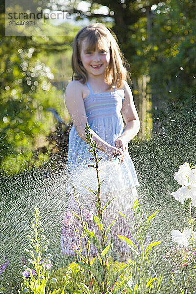 Young Girl Watering Flowers with Garden Hose