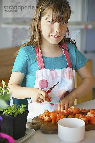 Smiling Young Girl Cutting Tomatoes