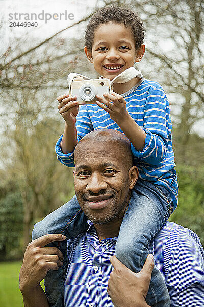 Father Carrying Son on Shoulders Outdoors