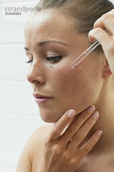 Beauty Portrait of Woman Applying Serum