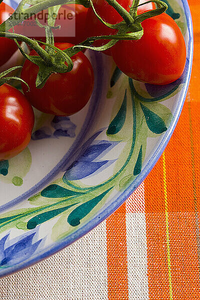 Close up of small plum tomatoes on the vine on a plate