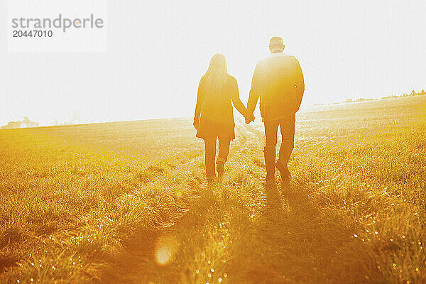 Couple Walking in a Field Holding Hands